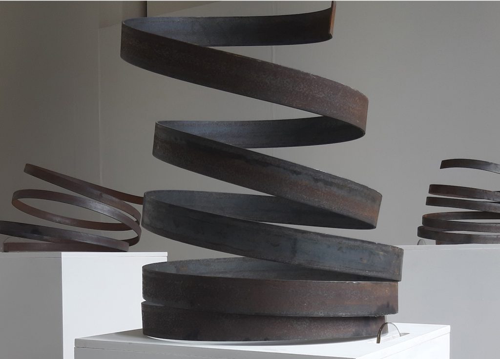 Student work by Caroline Clarke. Large metal spirals on plinths which hide mechatronic devices that nudge and wiggle the spirals, giving them the impression of independent movement