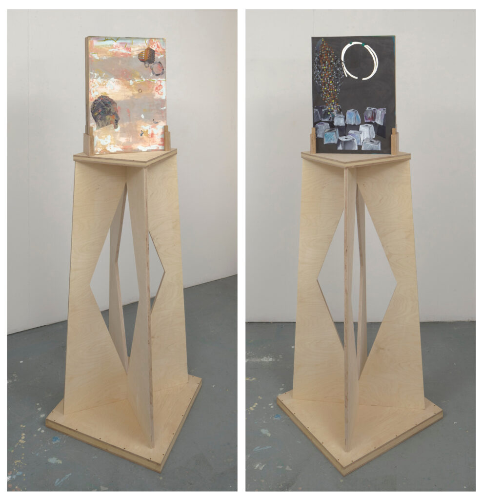 Two wooden pedestal stands, each displaying a rectangular artwork. The left artwork has abstract colors and shapes; the right one is darker with a circular design and geometric forms. Both stands have diamond-shaped cutouts.