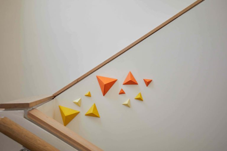 Artwork installed on staircase showing yellow and orange paper pyrimids