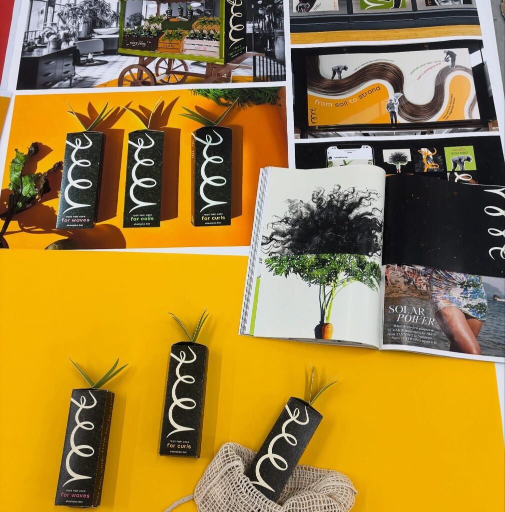 Several rectangular plant pots with curly white lines and green plants on top are displayed on a yellow surface. Behind them are open magazines and posters featuring plant and hair-themed images and creative layouts.