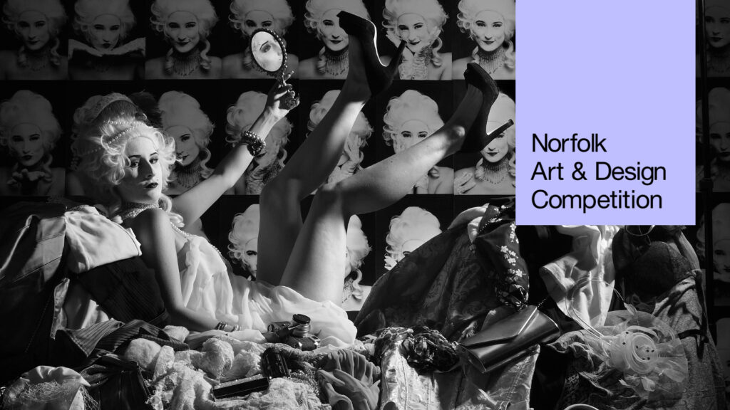 A person in 18th-century-style costume lounges amid clutter, holding a mirror and raising their legs, with pop art portraits of the same person behind. Text reads: "Norfolk Art & Design Competition. Explore our creative arts workshop opportunities.