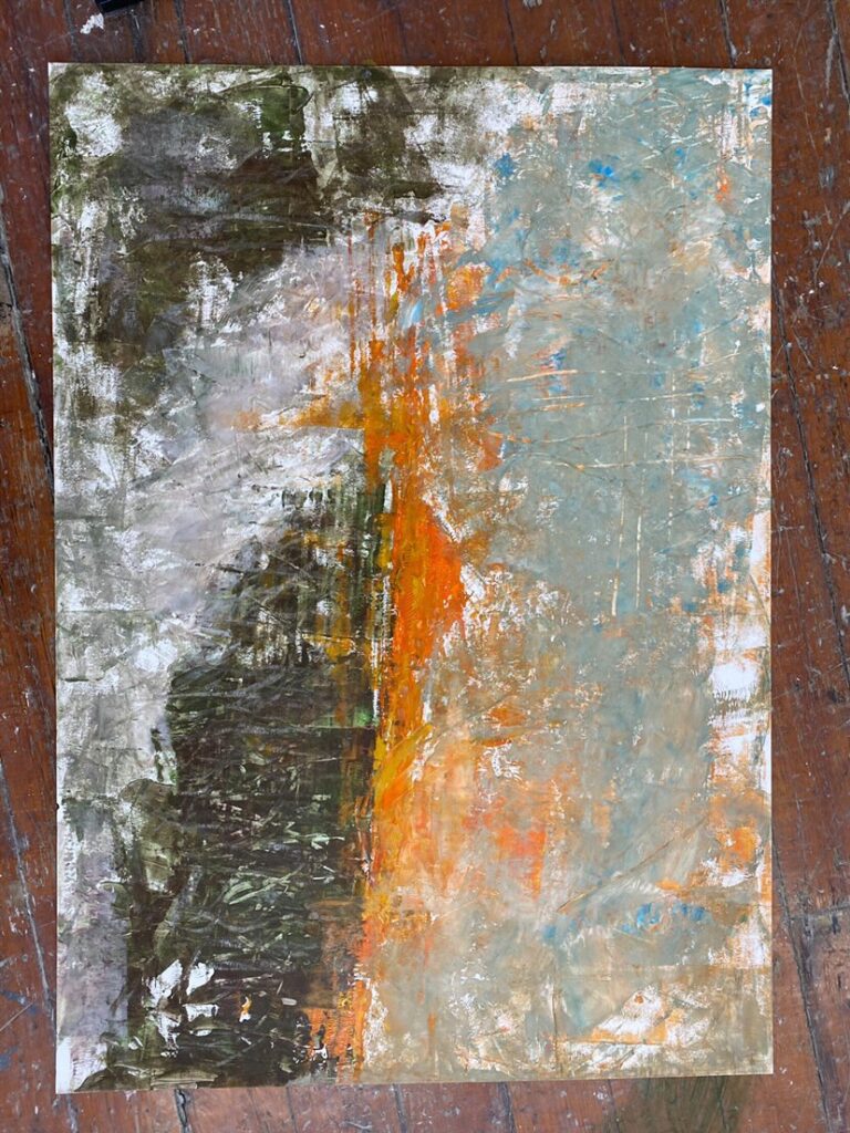 An abstract painting on paper features dark green and brown tones on the left, orange and yellow hues through the center, and light blue and white shades on the right, all blending with textured, brush-like patterns on a wooden floor.
